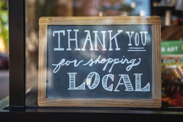 chalkboard sitting in a shop window that says, "Thank you for shopping local."
