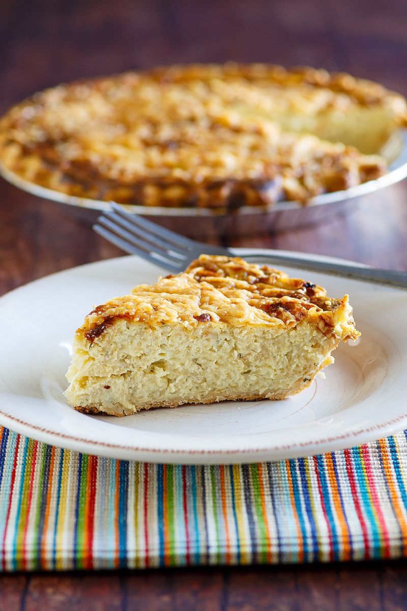 A slice of Vidalia onion pie sitting on a white plate on top of a colorful placemat.