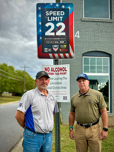 Two men standing by 22mph speed limit sign